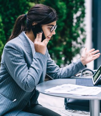 Finansal girişim web sitesinde, teknoloji ve iletişim kavramında bulunan başlangıç projesi değerlendirmeleriyle ilgili duygularını paylaşmak için iş ortağına seslenen neşeli tüccarın yan görünüşü