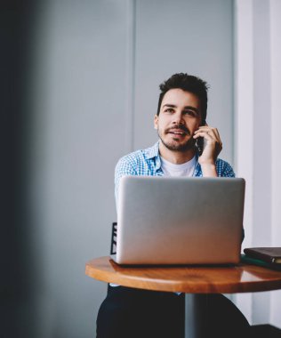 Başarılı erkek programcı modern dizüstü bilgisayar cihazı ile uzaktan çalışırken başlangıç projesi hakkında ayrıntıları tartışmak için meslektaşına çağrı, konuşmak için mobil uygulama kullanarak pozitif adam