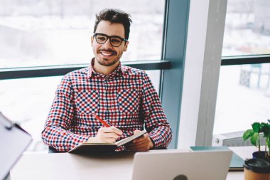 Mutlu neşeli adam girişimci optik gözlük modern ofiste ayakta kadın meslektaşım bilgi dinleme, başarılı bir çalışan netbook ile masaüstünde oturan ve işbirliği zevk