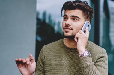 Yakışıklı adam açık havada oturan telefon görüşmesi sırasında bilgi açıklayan, hipster adam cep telefonu ile servis operatörü ile konuşma rezervasyon yapma danışmanlık detayları tartışıyor