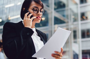 Cep telefonu üzerinden iş ortağı ile konuşurken zarif giyim ciddi kadın yönetici, cep telefonu üzerinden başlangıç projesi hakkında rapor kontrol kadın kontrol