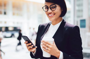 Optik gözlük şirket neşeli başarılı kadın sahibinin yarım uzunlukta portre gülümseyerek ve kamera bakarken ellerinde modern cep telefonu ve paket kahve tutarken mola sırasında