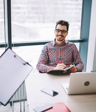Mutlu neşeli adam girişimci optik gözlük modern ofiste ayakta kadın meslektaşım bilgi dinleme, başarılı bir çalışan netbook ile masaüstünde oturan ve işbirliği zevk