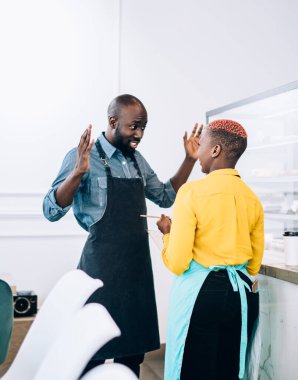 Düşük açılı Afro-Amerikan menajer garson ile konuşuyor ve açık modern mağazada tezgahın yanında durup hamur işi ile ilgili görüşleri açıklıyor.