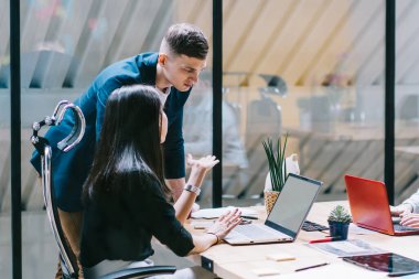 Dizüstü bilgisayarlarla çalışma alanı masaüstü bilgisayarlarında oturan erkek ve kadın ofis çalışanlarının genç ekibi. başlangıç projesi, ortaklık ve işbirliği konsepti ni geliştiren ortak çalışan grubu