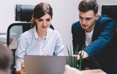Erkek ve kadın meslektaşları dizüstü bilgisayarda ofiste çalışma süresi boyunca online formatta proje bilgileri üzerinde beyin fırtınası, genç başarılı ortaklar haber okuma ve netbook üzerinde fikir paylaşımı