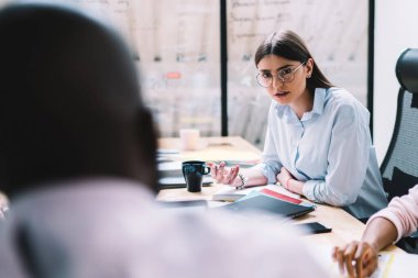 Ciddi genç iş kadını, yönetim kurulunda toplanırken, çeşitli meslekdaşlarına girişim projesi ve kurumsal anlaşma hakkında ısrarla fikir beyan ediyor.