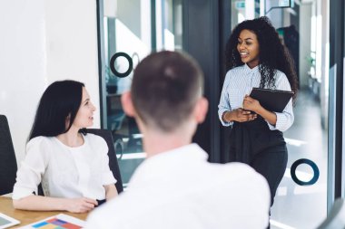 Dosyasıyla gülümseyen siyah kıvırcık kadın, yeni başlayanlar şirketine modern konferans odasındaki iş için geliyor.