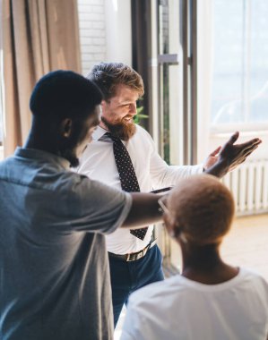 Tabletli ve içerik çeşitliliğindeki çeşitli satıcılar mutfak içini keşfederken modern ışık dairesinde minimalist iç mekanlarla konuşan farklı çiftler.