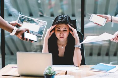 İş toplantısı sırasında isimsiz çalışanların arasında belgeler ve akıllı telefonlar ile çalışmaya odaklanırken, etnik yönetimin tapınakları ovması ve kaşlarını çatması