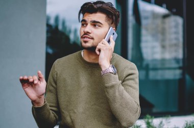 Yakışıklı adam açık havada oturan telefon görüşmesi sırasında bilgi açıklayan, hipster adam cep telefonu ile servis operatörü ile konuşma rezervasyon yapma danışmanlık detayları tartışıyor