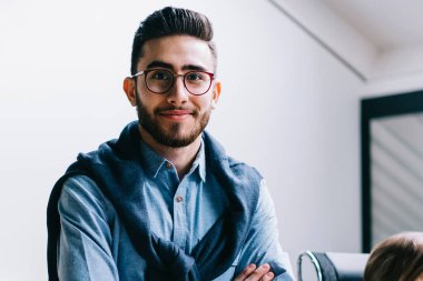 Pozitif başarılı adam uzman yarım uzunlukta portre ofis iç çapraz kolları ile ayakta iken kamera bakarken meslektaşları arka plan, iş ve meslek konuşurken