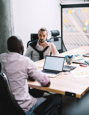 Çok ırklı genç şirket çalışanlarının arka planda cam tahtayla modern brifing ofisindeki proje kavramlarını tartışmaları