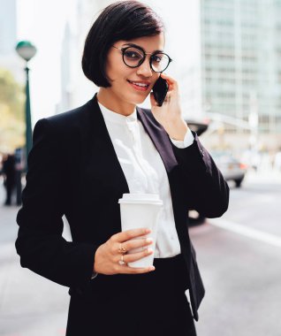 İş molası sırasında cep telefonundan finansal haberleri elinde kahve yle tartışan başarılı kadın girişimci, akıllı telefon uygulaması üzerinden partneriyle konuşan gülümseyen iş kadını