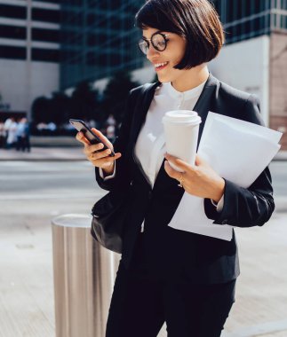 Gülen kadın sahibi modern sokakta dururken akıllı telefon üzerinden komik mesaj okurken, zarif giyim başarılı avukat kahve molası için zaman zevk telefon uygulaması iyi haber aldı