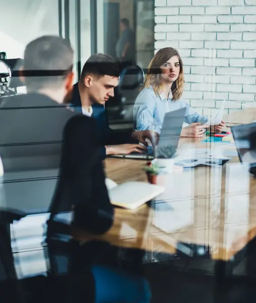 Kurumsal meseleleri ve stratejiyi tartışan çok ırklı iş adamlarının toplantı odasında kırtasiye malzemeleriyle masanın etrafında toplanması sayesinde.