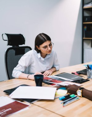 Erkek işçi, öğleden sonra ofisteki cep telefonuyla konuşurken kadın meslektaşına belge gösteriyor ve fikirlerini dile getiriyor.