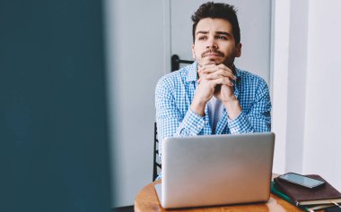 Düşünceli, odaklanmış, elleri sımsıkı bağlı bir adamdan dizüstü bilgisayarını kullanarak iş yerinde oturduğu yerden gözlerini kaçıran bir proje yaratıyor.