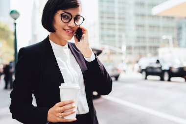 İş molası sırasında cep telefonundan finansal haberleri elinde kahve yle tartışan başarılı kadın girişimci, akıllı telefon uygulaması üzerinden partneriyle konuşan gülümseyen iş kadını