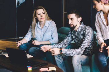 Gündelik giysiler içinde sakin iş arkadaşları masadaki yumuşak mavi koltukta otururken ve rahat modern ofiste netbook kullanırken iş konuşuyorlar.
