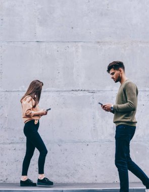Erkek ve kadın hipsters onların akıllı telefonlar bakarak açık havada yürüyüş gerçek hayat görmezden, kız ve adam sohbet ve gadget'lar bağımlısı ağ için cep telefonu kullanarak konsantre yürüyüş