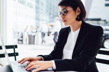 Optik gözlük konsantre kadın avukat kablosuz internet bağlantısı, iş adamları ve teknoloji kavramı ile modern dizüstü bilgisayar cihazı ile otururken web sitesinde bilet rezervasyonu