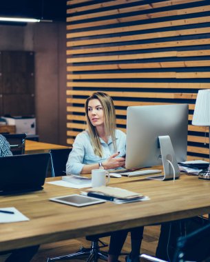 Çalışkan erkek ve kadın çalışma süreçlerini tartışıyor ve odasındaki ahşap masada dizüstü bilgisayar ve modern bilgisayar üzerinde çalışıyor.