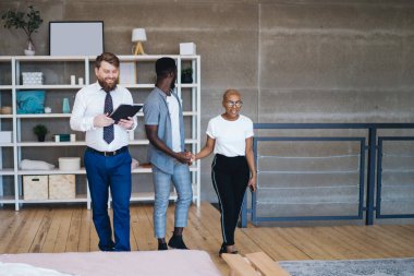 Resmi giysili gülümseyen adam ve ilgili Afro-Amerikan çift modern yatak odasında rahat bir şekilde yürüyorlar.