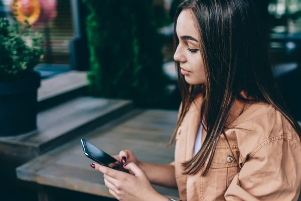 Genç esmer kadın uygulama üzerinden online sohbet arkadaşından cep telefonu okuma mesajı tutan, ağ için akıllı telefon kullanarak pensive hipster kız ve kafede eğlence harcama web sitesinde haber okuma