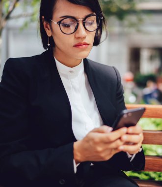 Ciddi kadın yönetmen iş ortakları ile iletişim kurmak için yeni bir uygulama yüklerken online bankacılık yapıyor, gözlük konsantre kadın finansal web sitesinde bildirim kontrol