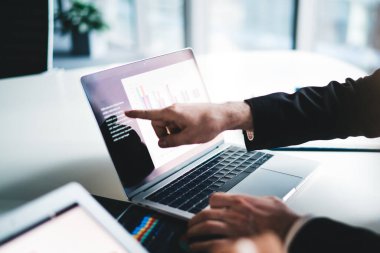 Beyaz masada oturan ve ofisteki dizüstü bilgisayarın ekranında çizelge ve çizelgelerle çalışan iş adamları.