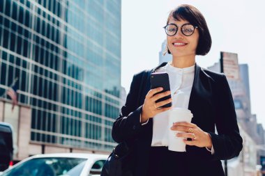 Finans bölgesinde kentsel ortamda iş molası sırasında akıllı telefon uygulaması üzerinden online iletişim kurmak için modern teknolojiyi kullanarak zarif takım elbiseli gülümseyen şirket yöneticisinin yarım uzunlukta portresi