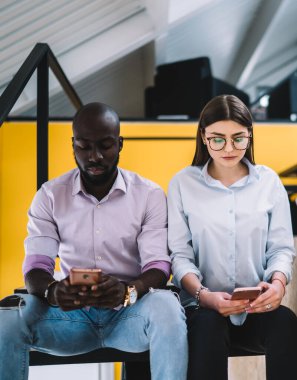 Modern üniversitede arkadaşça bir toplantı sırasında merdivenlerde yan yana otururken cep telefonlarıyla mesajlaşan gündelik giysiler içindeki farklı öğrencilere odaklandık.