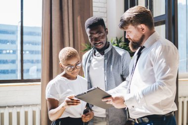 Resmi olarak sakallı bir erkek çalışanın elinde pano varken yeni evinde duran siyahi adam ve kadınla anlaşma detaylarını tartışırken yan görüntüsü.