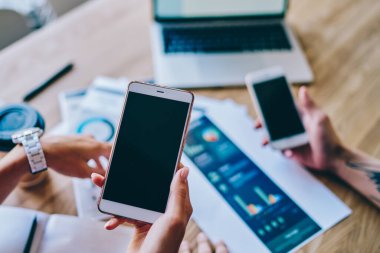 İş arkadaşlarının üst katlarından, günlük kıyafetlerini giyip masada oturmuş iş yerindeki kahve diyagramlarıyla cep telefonlarını izliyorlar.