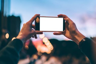 Boş dokunmatik ekranlı modern cep telefonuna seçici odaklanma. Fotoğraf çekmek için kamera kullanılıyor. Milenyum kadını, reklam sitesi için cep telefonuyla fotoğraf çekiyor.