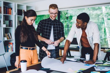 Düşük açılı düşünceli çalışanların dikkatle dinlediği Afrika kökenli Amerikalı bir uzman, elinde gazete ve kahveyle masada otururken, modern ofisin sıcacık tuvaletine gitmek için planda hata yaptığına işaret ediyor.