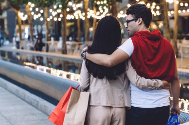 Günümüz modern çifti şefkat ve konuşmayla kucaklaşıp alışveriş torbalarıyla şehir caddesinde yürürken.