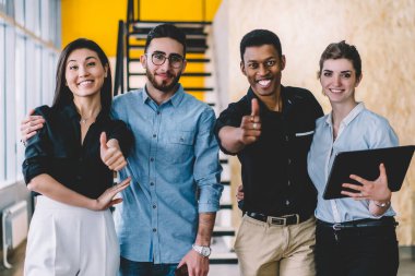 Ofiste poz veren başarılı genç, zeki erkek ve kadın iş arkadaşlarının yarım boy portresi. Mutlu erkek ve kadın çalışanlar kameraya bakıyor ve birlikte çalışırken gülümsüyor.
