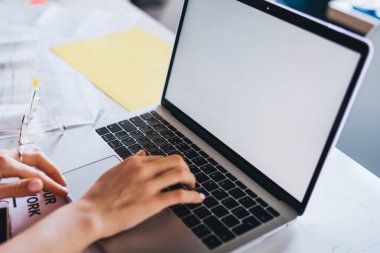 Dizüstü bilgisayarda çalışan ve araştırma için bilgi yazan yukarıdaki ekin sahibinden ofisteki belgelerle dolu masada oturan