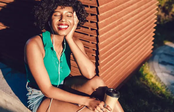 Cheerful African American female millennial feeling good from sunbath during summer day enjoying music with closed eyes,happy black woman listening motivation audio book via cellular app