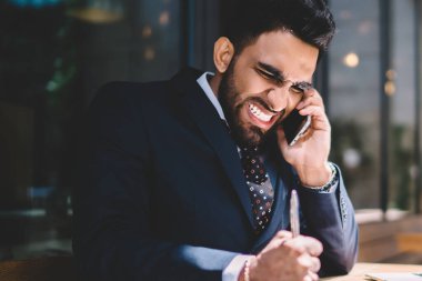 Saldırgan erkek bankacı, cep telefonuyla çalışan ile iletişim kurarken bilgisayarını kopyalama alanı olan dizüstü bilgisayarla masaya vuruyor. Öfkeli adam konuşan asistan ve kızgın hissediyor.