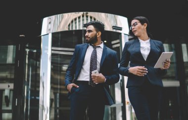 Takım elbiseli çok kültürlü erkek ve kadın çalışanlar ofis işi, iş adamları ve iletişim kavramı arasında modern teknolojinin faydalarını tartışıyor.