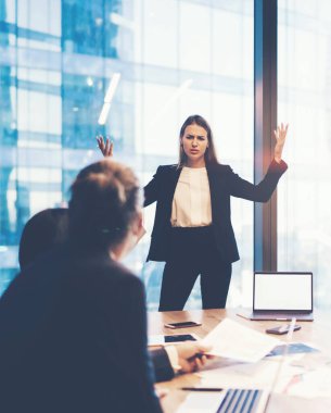 Ofis içi beyin fırtınası sırasında çalışanlarla tartışan kafası karışmış kadın yöneticiler, dizüstü bilgisayarla çalışan bir grup iş adamı.