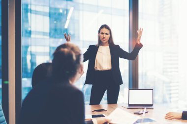 Ofis içi beyin fırtınası sırasında çalışanlarla tartışan kafası karışmış kadın yöneticiler, dizüstü bilgisayarla çalışan bir grup iş adamı.