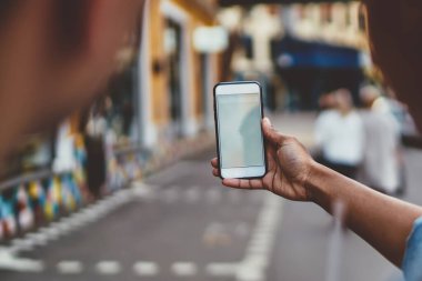 Uzamış elinizdeki akıllı telefon cihazını tutan ve şehir ayarlarının bulanık arka planında internet navigatörü kullanan kadın ve erkeğin arka plan görüntüsü. Seyahat uygulamalı modern cep telefonu.