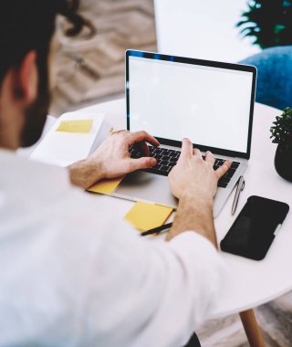 İnternet sitenizdeki reklam alanı, modern teknoloji konsepti ve iş mesafesi konsepti için ekran oluşturarak dizüstü bilgisayarda uzaktan çalışan yetenekli erkek yazılım geliştiricisinin arka görüntüsü