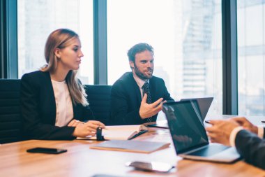 Konferans odasında yapılan beyin fırtınası sırasında şirketin finansal stratejisi konusunda işbirliği yapan bir grup şirket çalışanı masada otururken fikirleri tartışan başarılı ofis çalışanları.