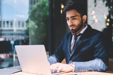 İspanyol erkek ekonomist, kafeterya wifi ile bağlantılı dizüstü bilgisayarda başvuru yoluyla rapor veriyor. Yönetmenle mesajlaştığı sırada resmi olarak giyinen yakışıklı adam belge için daktilo yazıyor.