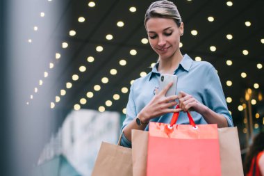 Kara Cuma günü alışveriş merkezinden alışveriş yaptıktan sonra elinde kağıt torbalarla gezen mutlu kadın, alışveriş saatinden sonra alışveriş yapan beyaz kadın, tanıtım alanında beklerken dinleniyor.